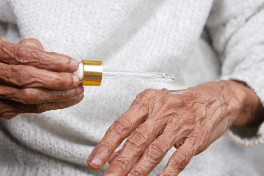 an older woman holding a small tube of liquid