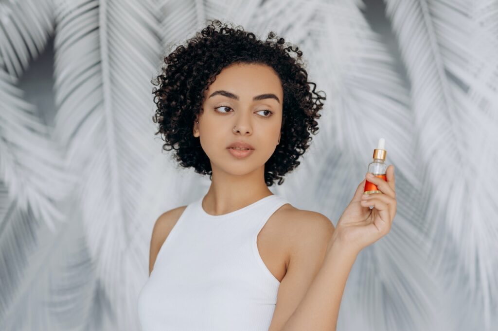 Woman in White Tank Top Holding A Bottle Of CBD Oil
